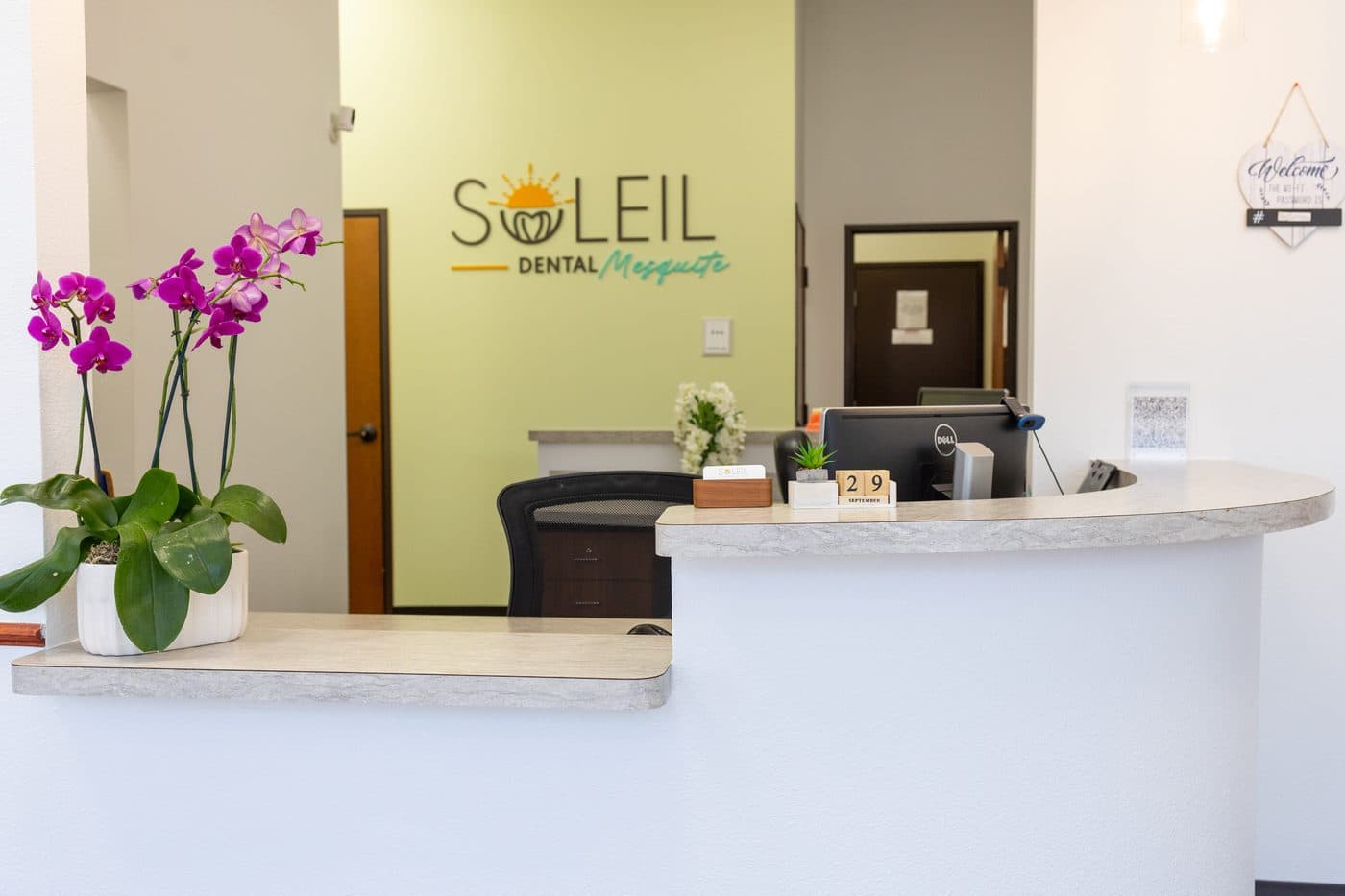 The Soleil Dental Mesquite front desk with orchids and the green logo wall